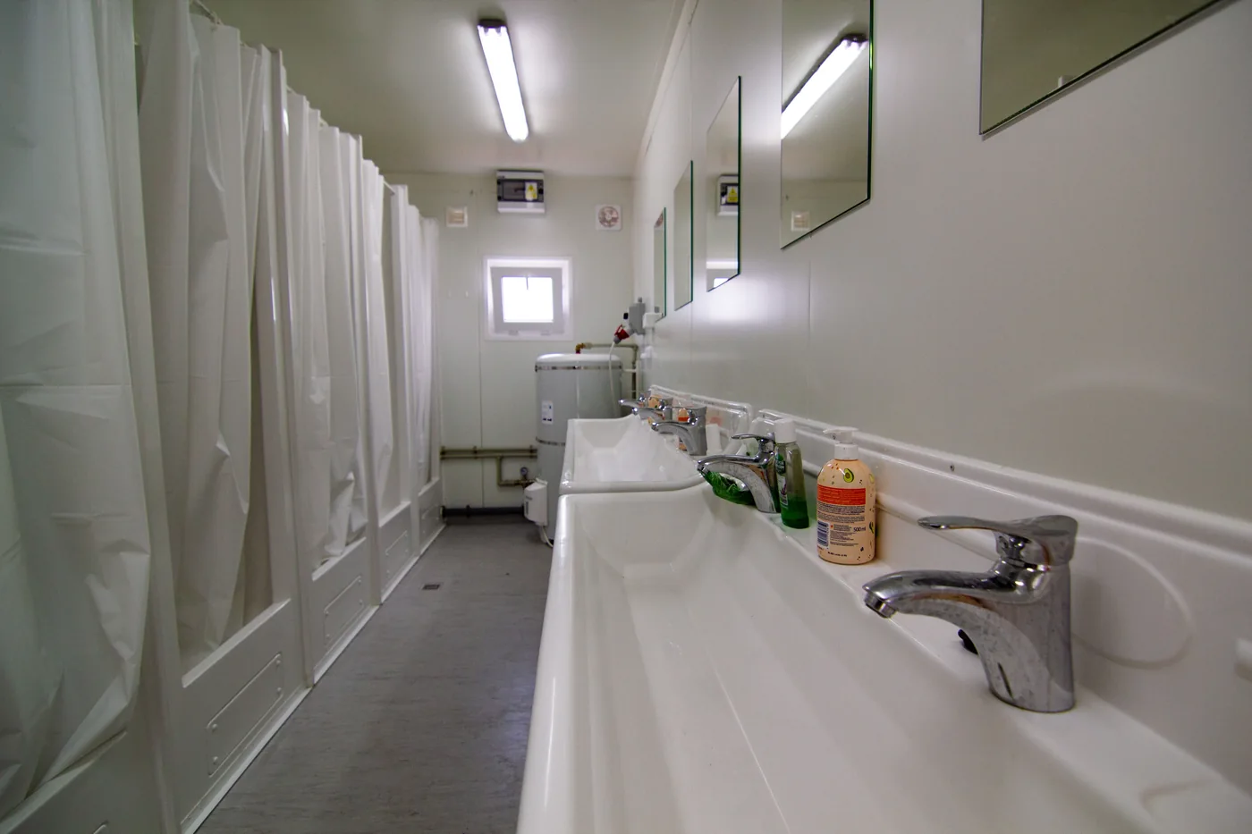 Shared washroom with sinks, mirrors and shower cubicles